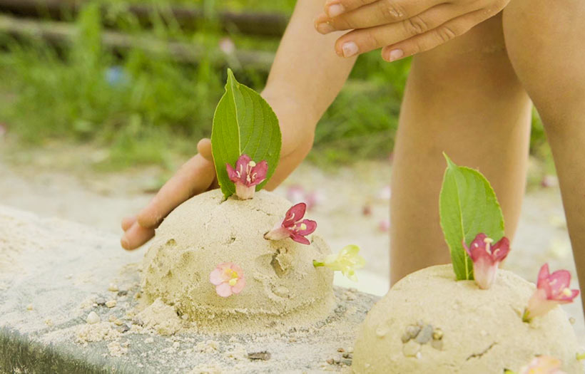 Detailaufnahme eines im Sandkasten spielenden Kindes.