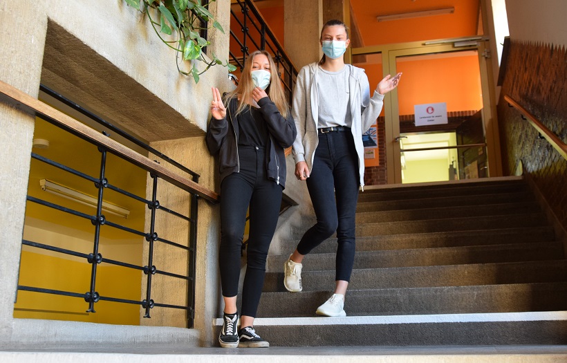 Zwei Mädchen stehen auf einer Treppe im Schulhaus der DPFA-Regenbogen-Oberschule rabenau und tragen eine Munden-Nasen-Schutz.