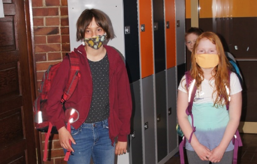 Ein Junge und ein Mädchen stehen im Flur der DPFA-Regenbogen-Schule Rabenau und tragen eine Mund-Nasen-Bedeckung.