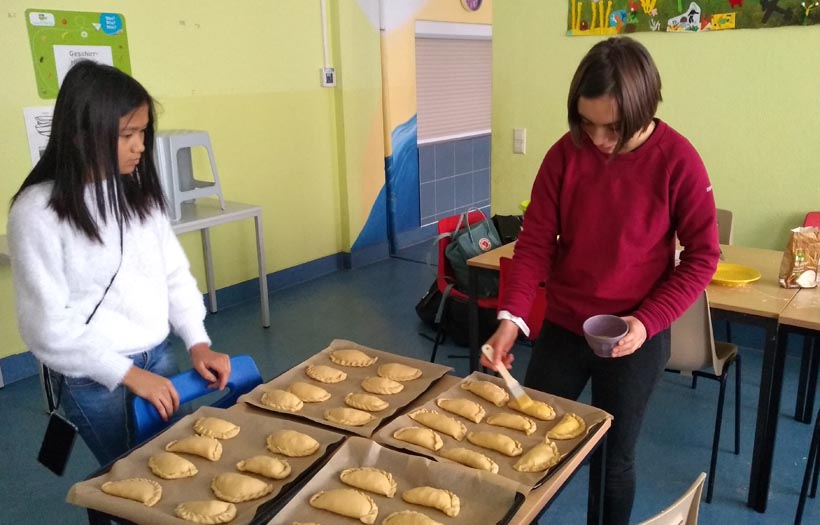 Zwei junge Mädchen bereiten Empanadas auf einem Backblech vor