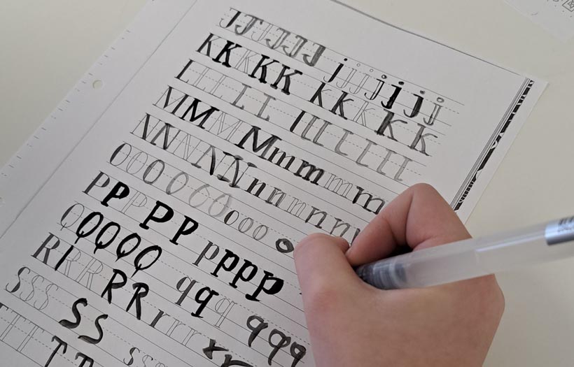 Hand mit Stift schreibt kunstvoll Buchstaben