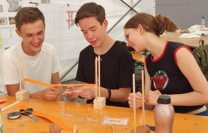 Drei Jugendliche konstruieren eine Brücke